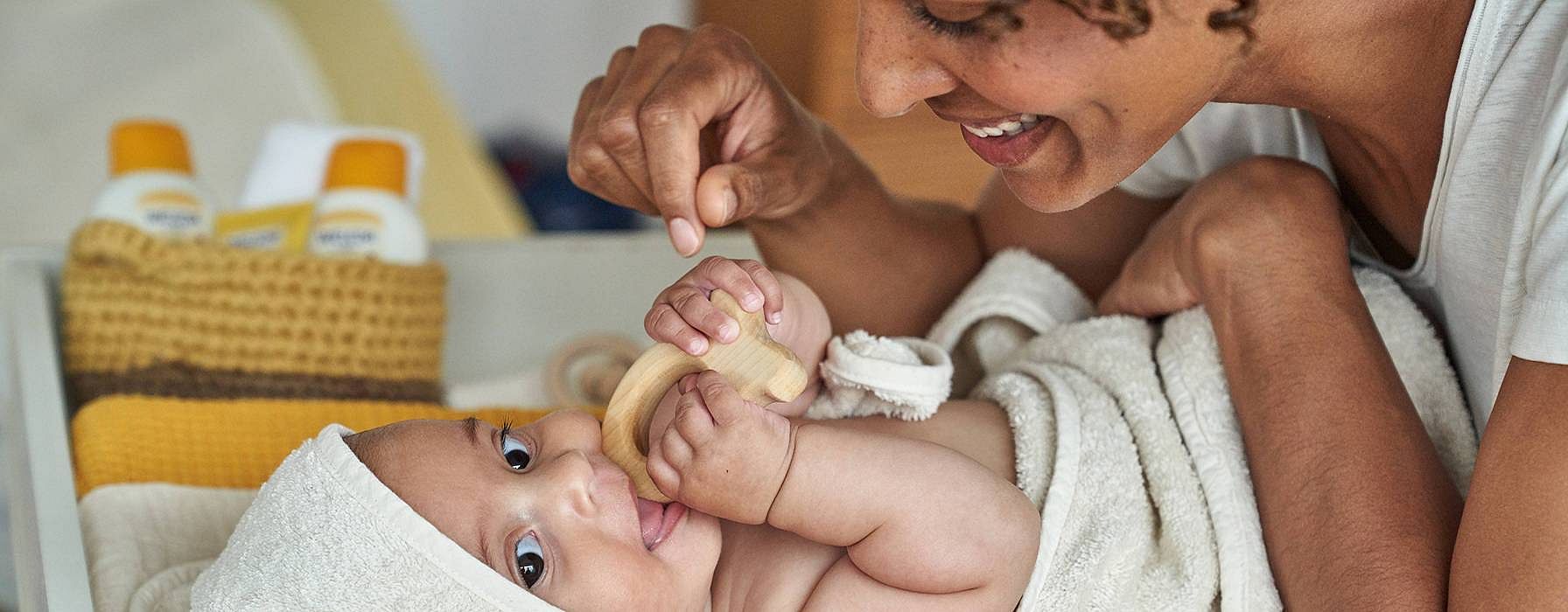 Mamma leker med baby på stellematte.