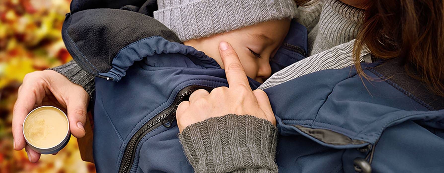 Mamma og baby koser seg ute blant høstløv.