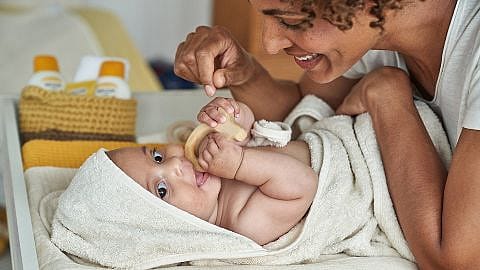 Mamma leker med baby på stellematte.