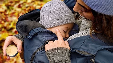 Mamma og baby koser seg ute blant høstløv.
